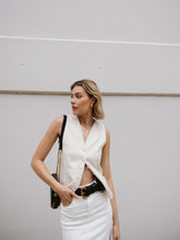 A lady wears a white denim skirt and a vest.